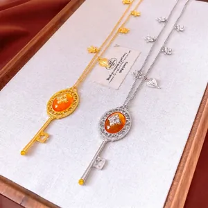 Vintage key pendant necklace with amber resin and floral accents in gold and silver