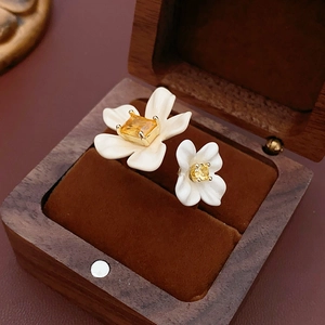 Detailed macro of gold plated flower ring with yellow zircon on a walnut jewelry box