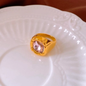 Macro shot of gold plated ring with a large square pink zircon stone on a white ceramic plate