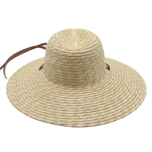 Detail shot of woven straw hat with wide brim and elegant brown leather drawstring