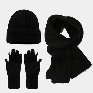 Detail of knit set featuring thick ribbed scarf, beanie, and gloves in solid black finish