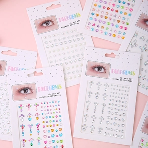 Close-up of 3D face gems and nail art stickers with pearls and heart shapes on pink backdrop