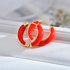Close-up of red enamel geometric hoop earrings with gold edges on white background