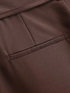 Dettaglio ravvicinato di cuciture e trama delle tasche sui pantaloni marrone scuro