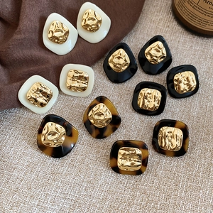 Close-up of vintage earrings with leopard resin and gold hammered metal inserts