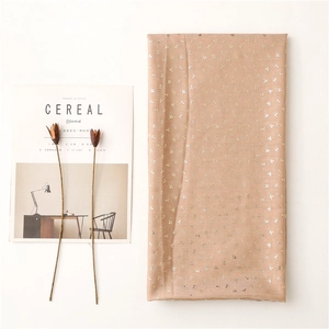 Detail of light brown headscarf featuring gold leaf prints beside minimalist magazine