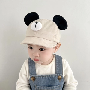 Close-up of cute beige baby baseball cap with animal ears and denim overalls