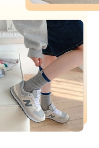 Detail of gray striped crew socks paired with gray sneakers and denim shorts on wood floor