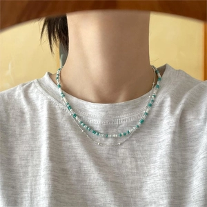 Detail of layered sterling silver necklace with turquoise and white beads on neck