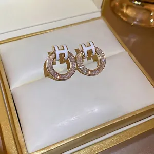 Gold-plated H-shaped stud earrings with white enamel and sparkling zircon ring drop