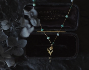 Detail of vintage tulip pendant necklace with green beads and 18K gold plated steel chain