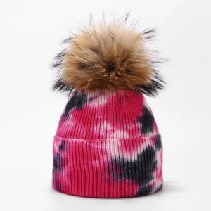 Detail of tie-dye knit beanie with thick ribbed texture and fluffy faux fur pom pom