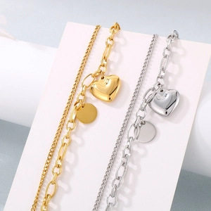 Detail of 18K gold and silver double-layered heart charm bracelets on geometric stands
