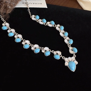 Close-up of bohemian turquoise beads and silver metal details on a dark velvet background
