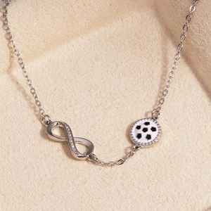 Nahaufnahme eines silbernen Unendlichkeits-Armband mit Zirkonsteinen und Fußball-Anhänger