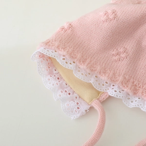 Pink knit baby bonnet with white lace trim and floral texture for newborn girls