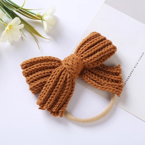 Detailed view of a brown knitted bow baby headband with elastic nylon band and soft texture