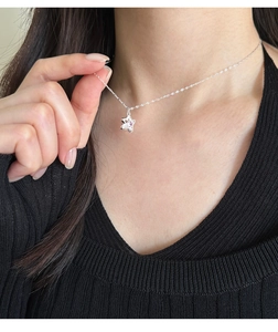 Detail of s925 silver necklace with pink zircon star pendant worn by a model
