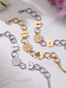 Detail of 18k gold plated stainless steel bracelets with coin pendants on marble background