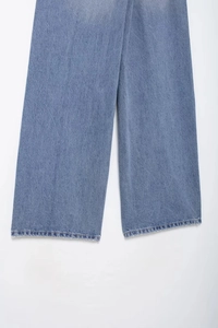 Gros plan sur les coutures de l'ourlet et la texture denim bleu clair du pantalon