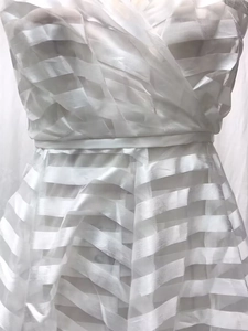 Dettaglio dell'abito da sposa a righe bianche con scollo a V e texture sulla vita