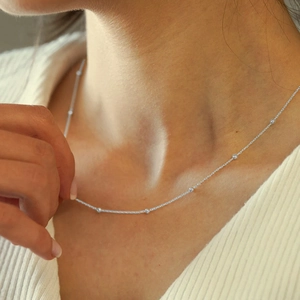 Close-up of minimalist silver beaded chain necklace worn on a female neck for daily wear