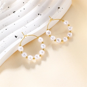 Detailed macro of gold twisted hoop earrings featuring lustrous white pearls