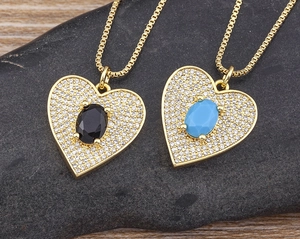 Detail of gold heart pendant necklace featuring black and turquoise pave zircon stones