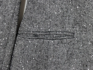 Macro shot of herringbone wool blend fabric texture and welt pocket detail on blazer