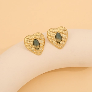 Detail of vintage heart stud earrings with grey oval gemstones and hammered gold metal