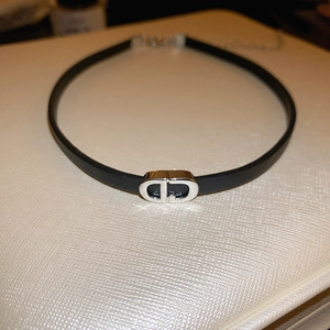 Detail view of a black leather choker featuring a polished silver metal CD buckle design
