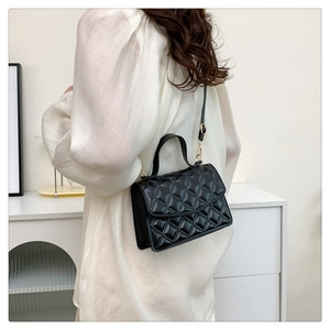 Detail of a black quilted crossbody bag featuring gold-tone hardware and leather texture