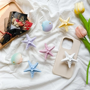 Detail of colorful seashell and starfish phone sockets on a textured beige phone case