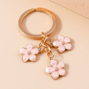 Detailed close-up of pink cherry blossom pendants on a gold-plated alloy keychain
