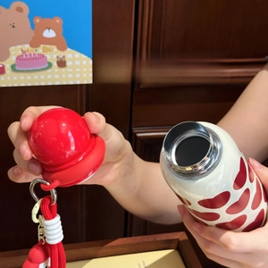 Detail of cute round ball leak-proof lid with red heart patterns on white stainless steel cup