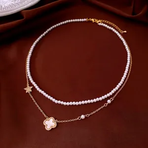 Elegant double-layered necklace featuring white pearls, gold chain, and clover flower pendant