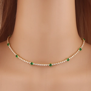Close-up of gold tennis necklace with alternating green and white cubic zirconia stones