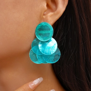 Close-up of layered turquoise geometric circle drop earrings on model for vacation look