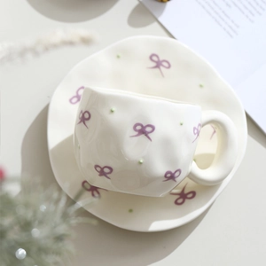 Top-down macro view of handmade cream ceramic cup with purple bow and green polka dots