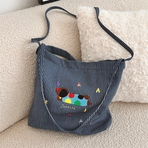 Detailed close-up of blue striped canvas bag with cute cartoon animal embroidery