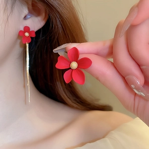 Detail of red five-petal flower earrings with golden core and elegant long tassels