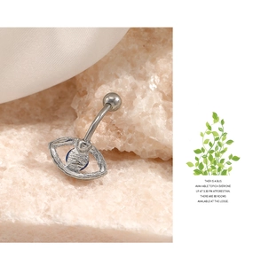 Macro shot of evil eye belly ring with blue gemstone on pink stone and white silk fabric