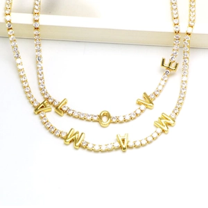 Macro shot of gold tennis chain featuring zircon pavé LOVE and MAMA letter pendants