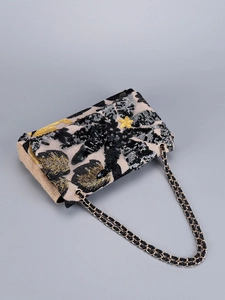 Close-up of beige woven shoulder bag featuring gold and black sequined leaf embroidery