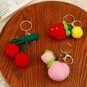 Handmade crochet fruit keychains featuring cherry peach and strawberry on wooden tray