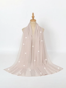 Detail of elegant beige chiffon shawl featuring sparkling rhinestones on wood mannequin