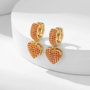 Golden heart drop earrings with micro-paved orange zircons on a white minimalist stage