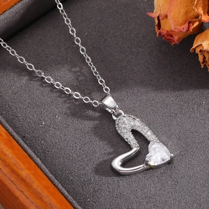 Vista macro di una collana a cuore traforato con diamanti brillanti e pietra centrale