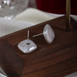 Minimalist Baroque square freshwater pearl studs on a wooden display stand for women