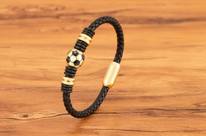 Detail of black braided leather bracelet featuring a golden soccer bead and magnetic clasp